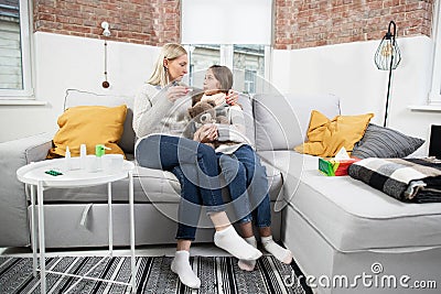 Family, healthcare, flu and cold concept. Stay at home. Mother taking care of her cute sick teen daughter suffering from Stock Photo