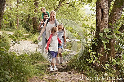 Family Hiking Along Path By River In UK Lake District Stock Photo