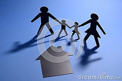 Family holding hands with jigsaw puzzle house Stock Photo