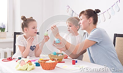 Family holiday Easter: Mother helps her daughter to paint an Easter egg. Stock Photo