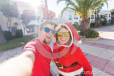 Family, holidays and christmas concept - happy couple in santa costumes taking selfie together Stock Photo