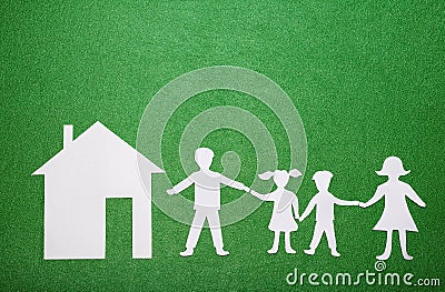Family and home concept. Parents and children holding hands. Paper family figures and house on green textural background Stock Photo