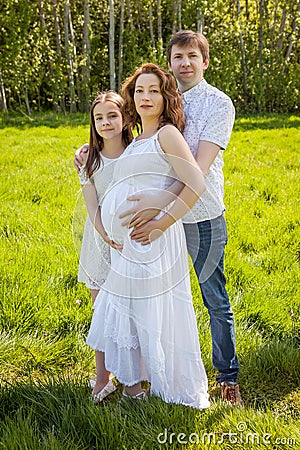 Family husband pregnant wife and daughter expecting baby green park outside Stock Photo