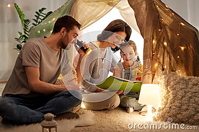 Happy family reading book in kids tent at home Stock Photo