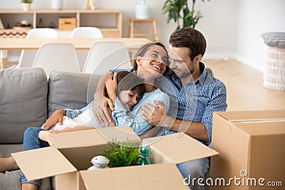 Family with kid embracing on sofa moving in new home Stock Photo