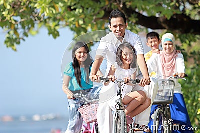 Family with kids enjoy riding bicycle outdoor in the beach Stock Photo