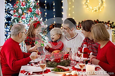 Family with kids having Christmas dinner at tree Stock Photo