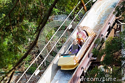 Family with kids on roller coaster in amusement theme park. Children riding high speed water slide attraction in entertainment fun Stock Photo