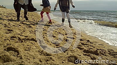 Family legs play beach together at sea shore. Fun people walking by ocean waves. Stock Photo