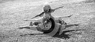 Family leisure time. Family lying on grass in park. Parents giving child piggybacks in park. Stock Photo