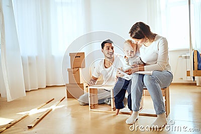 Family reading instruction and assemble furniture together at living room of new apartment pile of moving boxes on Stock Photo