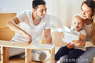 Family reading instruction and assemble furniture together at living room of new apartment pile of moving boxes on Stock Photo