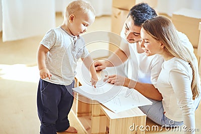 Family reading instruction and assemble furniture together at living room of new apartment pile of moving boxes on Stock Photo