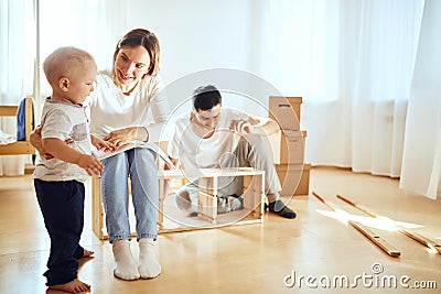 Family reading instruction and assemble furniture together at living room of new apartment pile of moving boxes on Stock Photo