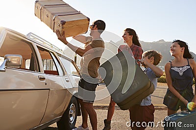 Family Loading Luggage Onto Car Roof Rack Ready For Road Trip Stock Photo