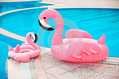 Family look. Two Pink pool floats flamingo by blue water, pool party toy. Giant Inflatable Swimming Ring. Summer vacation holiday Stock Photo