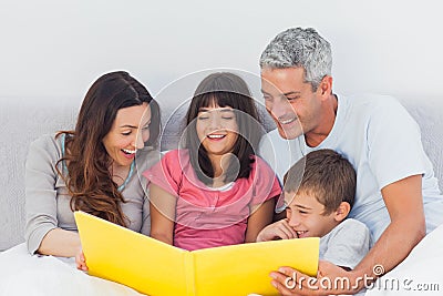 Family looking together at their photograph album in bed Stock Photo