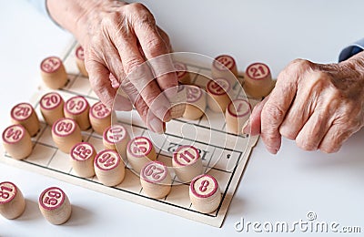 Family Lotto board game. The hands of an elderly woman put the barrels on the cards Stock Photo