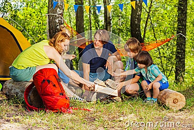 Family making camp fire with fireplace log pieces Stock Photo