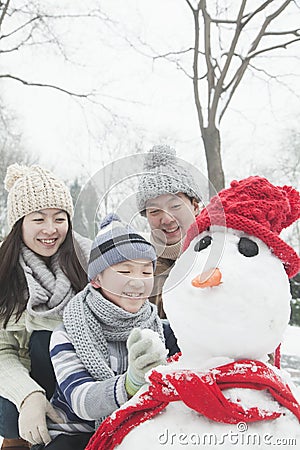 Family making snowman in a park in winter Stock Photo