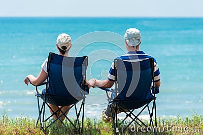 Family man and woman relax and unwind in camping chairs Stock Photo