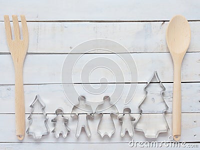 Family metal cookie or biscuit cutter composed of father, mother, brother, sister and pine tree with wooden spoon and fork or ladl Stock Photo