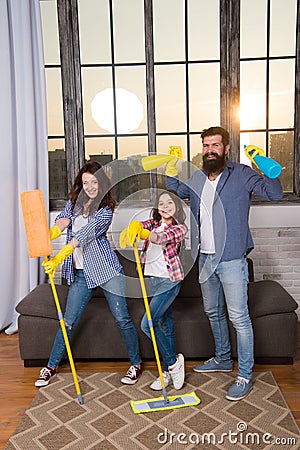 Family mom dad and daughter with cleaning supplies at living room. We love cleanliness and tidiness. Cleaning together Stock Photo