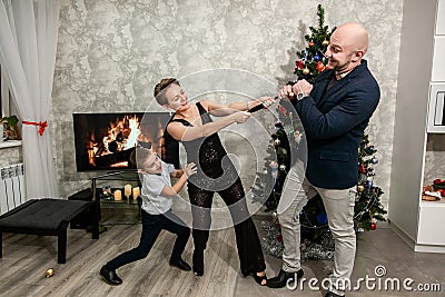 Family mom, dad and son fool around and play near the Christmas tree in their apartment Stock Photo