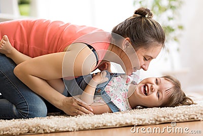 Family - mom and daughter having a fun on floor at home. Woman and child relaxing together. Stock Photo