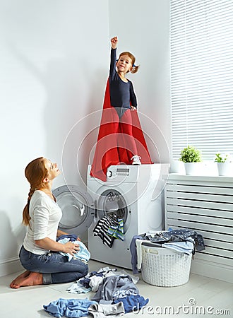 Family mother and child little superhero helper in laundry room Stock Photo