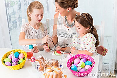 Family with mother and kids coloring Easter eggs Stock Photo