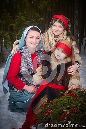 Family with mother, teenage girl, and little daughter dressed in stylized medieval peasant clothing in winter forest Stock Photo