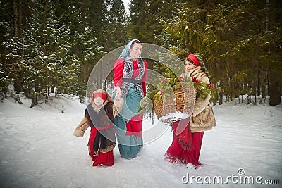 Family with mother, teenage girl, and little daughter dressed in stylized medieval peasant clothing in winter forest Stock Photo