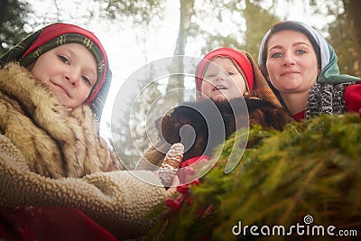 Family with mother, teenage girl, and little daughter dressed in stylized medieval peasant clothing in winter forest Stock Photo