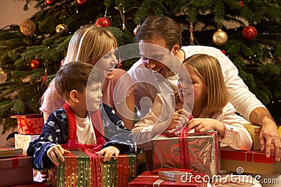 Family Opening Christmas Present In Front Of Tree Stock Photo