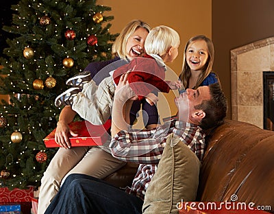 Family Opening Presents In Front Of Christmas Tree Stock Photo