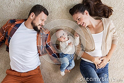 Happy family with baby lying on floor at home Stock Photo