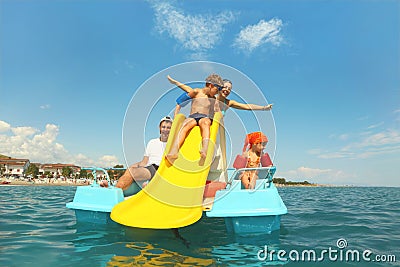 Family on pedal boat with yellow slide in sea Stock Photo