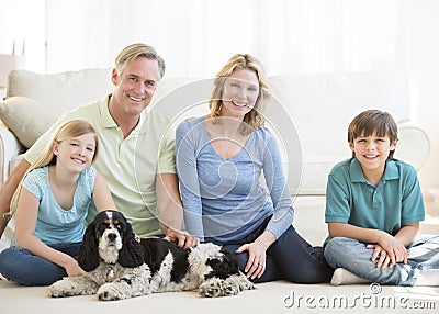 Family With Pet Dog Sitting On Floor In Living Room Stock Photo