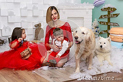 Family photo portrait. Mom and her two children and two white dogs in red clothes celebrate the Chistmas, new year Stock Photo
