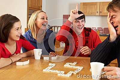 Family Playing Dominoes In Kitchen Stock Photo