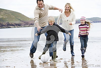 Family playing football on beach Stock Photo