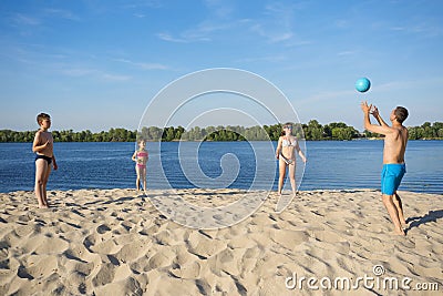 The family plays beach volleyball on the sandy shore of the river. A healthy way of life Stock Photo