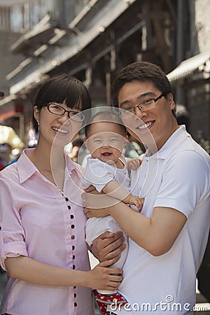 Family portrait, father is holding the baby, smiling and looking at camera Stock Photo
