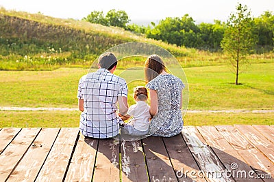 Family portrait. Picture of happy loving father, mother and their baby outdoors. Daddy, mom and child against green hill Stock Photo