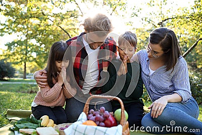 Family praying before meal in park Stock Photo