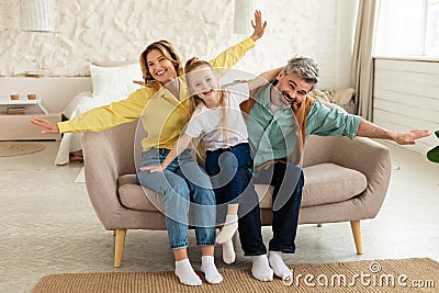 Family With Preschool Daughter Having Fun Posing Spreading Hands Indoor Stock Photo