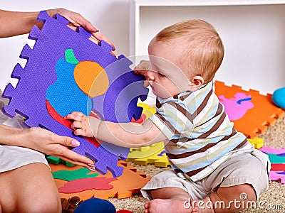 Family puzzle making mother and baby. Child jigsaw develops children. Stock Photo