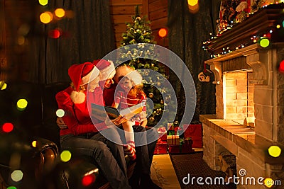 Family read stories sitting on coach in front of fireplace in Christmas decorated house interior Stock Photo