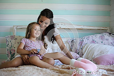 Family reading bedtime. Pretty young mother reading a book to daughter. Stock Photo